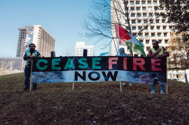 Imajen ida ne'ebé hatudu negosiasaun ceasefire entre Israel no Hezbollah, ho diplomatas sira tuur iha meza, no bandeira nasau