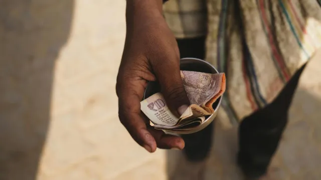Imajen hatudu inan ida iha India ne'ebé simu envelope osan husi programa PMMVY, ho sorrisu iha nia rosto, iha ambiente ki'ik 