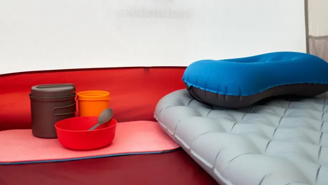 Imagem ida hatudu kobertor ultralight iha tenda, ho equipamentu sientífiku ba teste térmiku no peso.