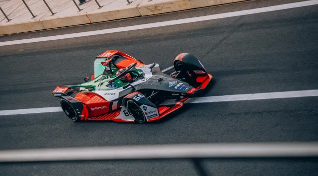 Imajen ida ne'e hatudu tolu elementu: karru korrida Formula E husi Porsche, edifísiu históriku restorante iha Savannah, no ma