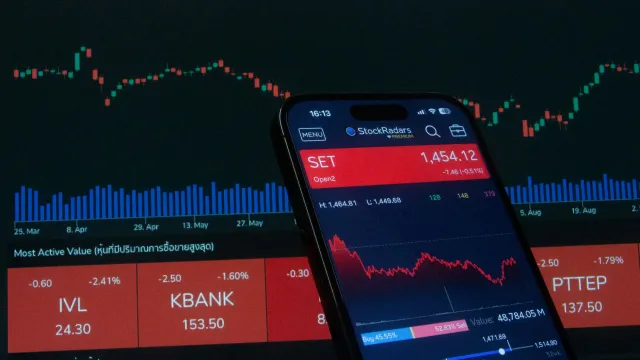 Imajen mostra ema sira iha sala reuniu, haree grafiku ekonomi no dokumentu, representa estratéjia investimentu ne'ebé segurá 