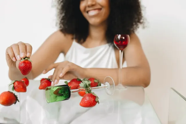 Imajen hatudu ema ida kaer glass ho ai-tahan, ho fundu sirkulu verde no simbolu konsiensia kanser, ho fruta fresku iha meja, 