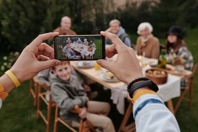 Imajen ida hatudu familia iha meja han, maibe sira hotu uza smartphone hela, hatudu tanba sa teknolojia bele estraga ligasaun