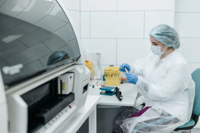 Sientista ida analiza dados genética iha laboratóriu, ho komputador no mikroskopiu iha meja