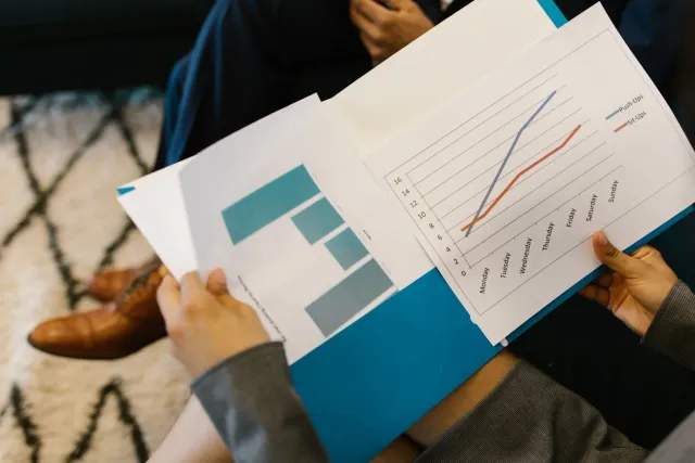 Imajen ida hatudu enkontru negósiu ho dokumentu relatóriu sustentabilidade no gráfiku finanseiru iha meja, hanesan ilustrasau