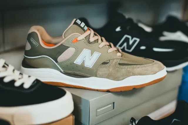 Sneaker Kith ho New Balance 2011 iha kor azul no branku, ho detallu dezign orijinál, iha fundu ne'ebé lais