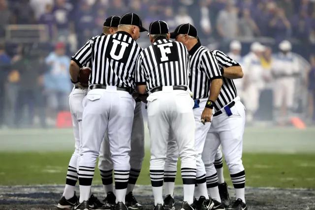 Ema barak iha estádiu NFL sira haree ho atensaun ba jogador sira no árbitru iha kampu, hatudu oinsá desportu liga malu ho jus