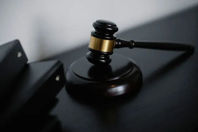 Imajen hatudu ema ida tuir iha tribunal, iha kotuk iha komputadór ne'ebé hatudu modelu AI Fable 5, simboliza kazu kontra Gove
