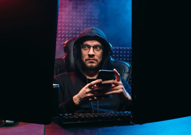 Ema ida tuur iha oin komputador ho ekrã barak, hatudu Summer Game Fest 2026 no InfoWars reboot, simboliza konsumu media moder