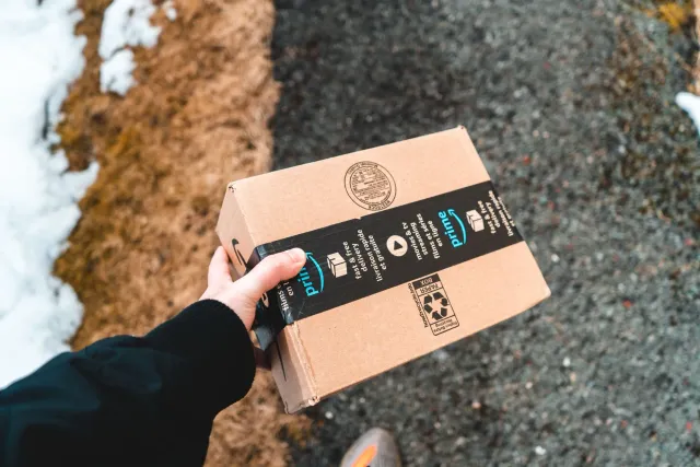 Imajen ida hatudu Kamioi entrega Amazon ho fornese barak iha dalan estrada iha Índia, ho sidade iha tempu udan, hanesan simbo