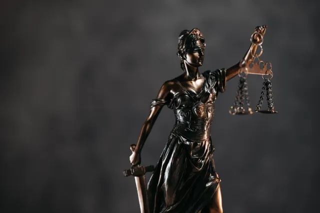 Imajen hatudu folha jornal ho títulu demanda kontra OpenAI no Microsoft, iha meja tribunal, ho ordenadór no dokumentu legál, 