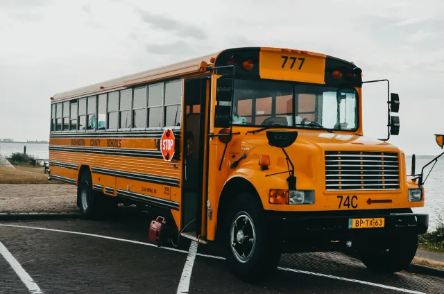 Elizabeth Banks hanesan Ms. Frizzle iha filme live-action Magic School Bus, ho nia vestidu karakterístiku no bus eskola iha k