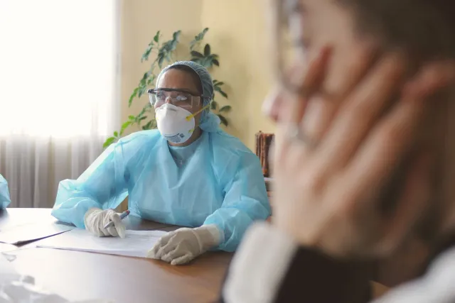Imajen ida hatudu traballador saúde iha Uganda hatoo ekipamentu protesaun durante surtu Ebola, ho fundu ospitál ne'ebé simple
