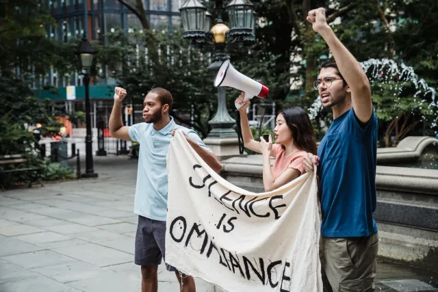 Imajen ida hatudu kusén ho desenju ativista no letra 'Small Business Activism' iha fundu neon, ho ema ki'ik sira hamriik hamu