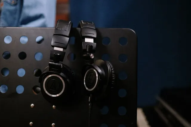 Pesoál ida uza headphone iha estúdiu músika ho ekipamentu áudio modernu hanesan DAC no amplificador, simboliza uniaun entre t