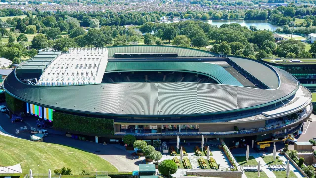 Imajen ida ne'ebé hatudu estadiu tenis Wimbledon iha rai laran, ho jogador sira jogu iha korti grama, ne'ebé reprezenta futur