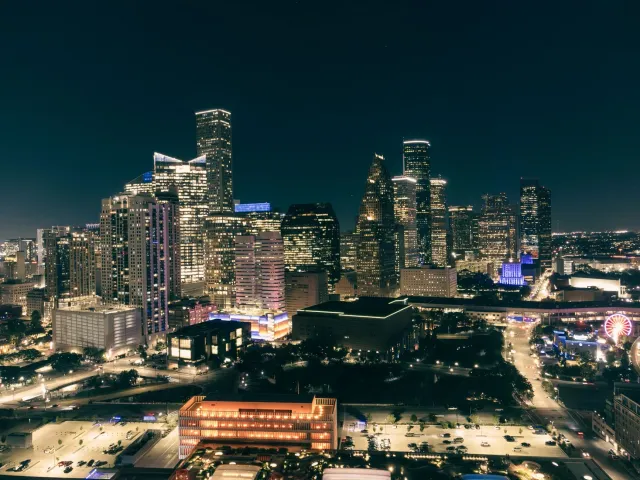 Vista husi sidade Houston iha Texas ho edifísiu modernu no sinal neon, reprezenta ambiente negósiu ne'ebé dinámiku