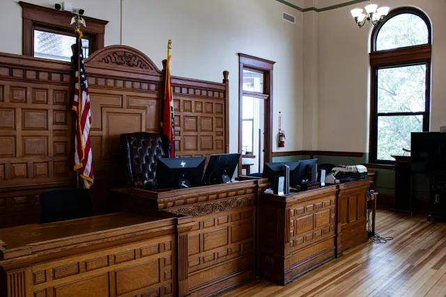 Imajen husi tribunal imigrasaun iha Estados Unidos ho juiz no imigrante sira tuur hela, hatudu tensaun no seriedade iha kazu 
