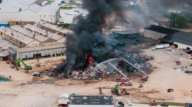 Asu nabilan boot husi fogo iha scrapyard Milwaukee, sinal laranja no fumo nakonu iha lalehan, besik uma sira