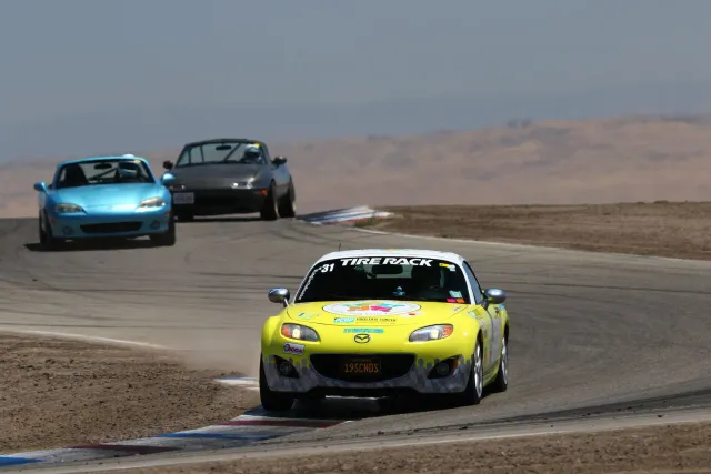 Mazda MX-5 karru desportivu aksesível kór vermellhu hela iha dalan laran, ho nia aas ki'ik no modelu elegante, ne'ebé hatudu 