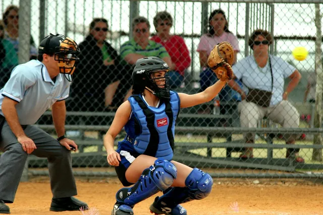 Jogador softbol luta iha partida importante, ho torcida iha kotuk, hatudu espíritu ekipa no kompetisaun