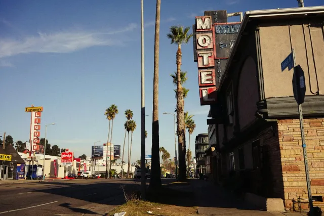 Vista husi hotél modernu iha Los Angeles ho luz neon no arranha-séu iha kotuk, ne'ebé hatudu ambiente negósiu no teknolojia