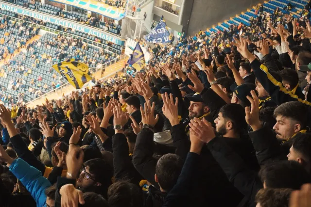Ema barak iha estádio desportu, sira hamriik no haksoit tanba kontente, ho luz boot no bandeira sira iha kotuk, hatudu ambien