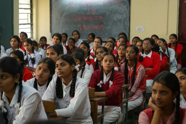 Labarik tribal iha sala aula ho komputador no livru, hatudu edukasaun modernu ne'ebé hetan liu husi programa EMRS iha Bihar.
