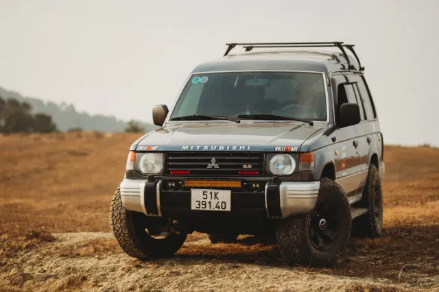 Imajen konseituál: logu Visa no Google iha fundu teknolojia, karreta Mitsubishi Pajero iha estrada off-road, no pitxer baseba
