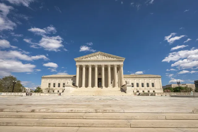 Imajen hosi edifísiu Tribunal Supremu EUA iha Washington D.C., ho bandeira americana iha leten, hanesan símbolu ba lei sidada