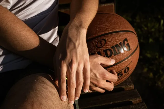 Imajen ida hatudu jogadór basket NBA tuur ho ulun tun, ho luz sombriu, simboliza presaun mental no estresse ne'ebé atleta sir