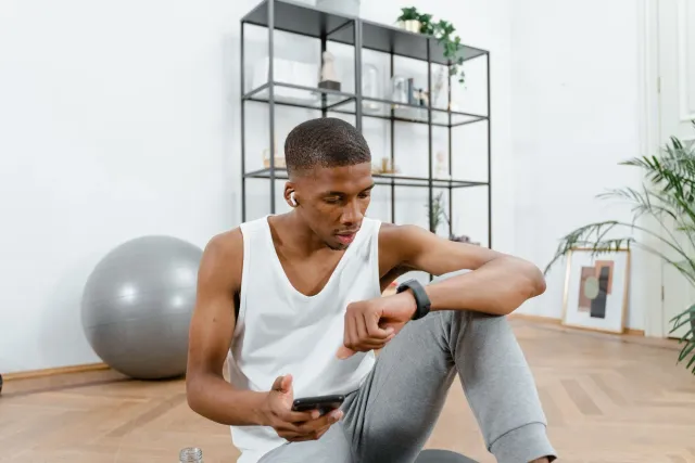 Mane ida uza fitness tracker iha laran no haree dadus iha ekrã, simboliza oinsá teknolojia ajuda kontrolu saúde sperm ho dado