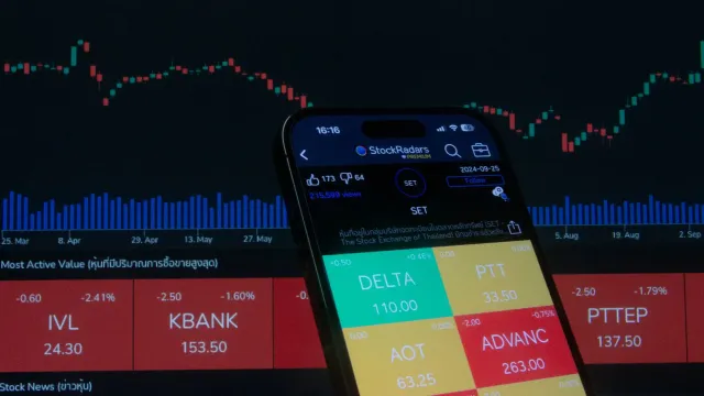 Imajen ne'ebé hatudu teknolojia AI stock trading ho komputador no gráfiku finanseiru iha futuru
