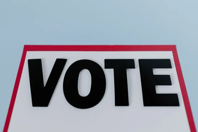 Imajen ida hatudu plaka kampanha by-election iha Makerfield, ho tenda no edifísiu negósiu lokal iha kotuk, ilustra ambiente p