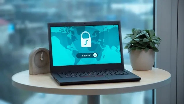 Imajen hatudu laptop Framework modular iha meja, ho ekrã hatudu logo Xbox Games Showcase no símbolu seguransa dadus, hodi ilu