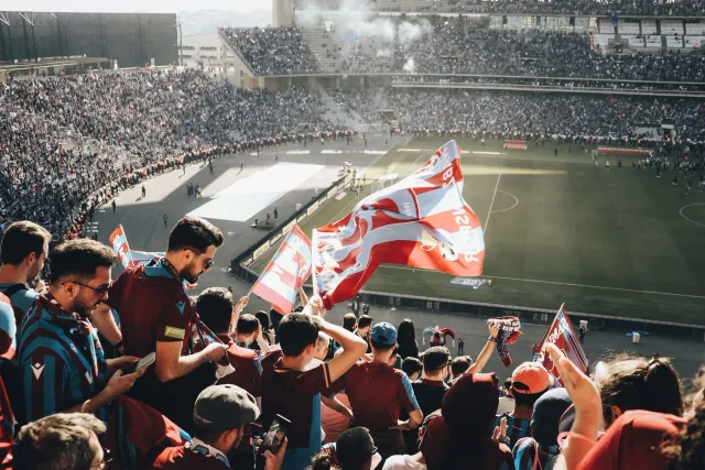 Ema barak hamriik iha estadiu hodi haree partida futebol, hatudu aspetu umanu iha desportu