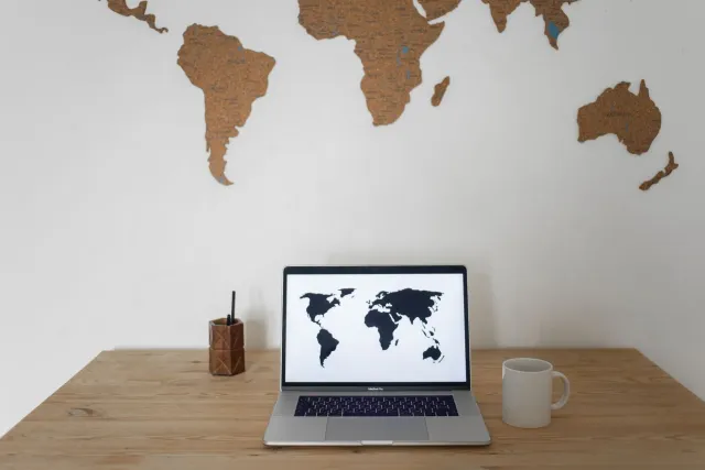 Imajen mostra ema sira iha escritóriu hanesan espertu negósiu ne'ebé analiza mapa mundu no laptop hanesan atu haree risco glo